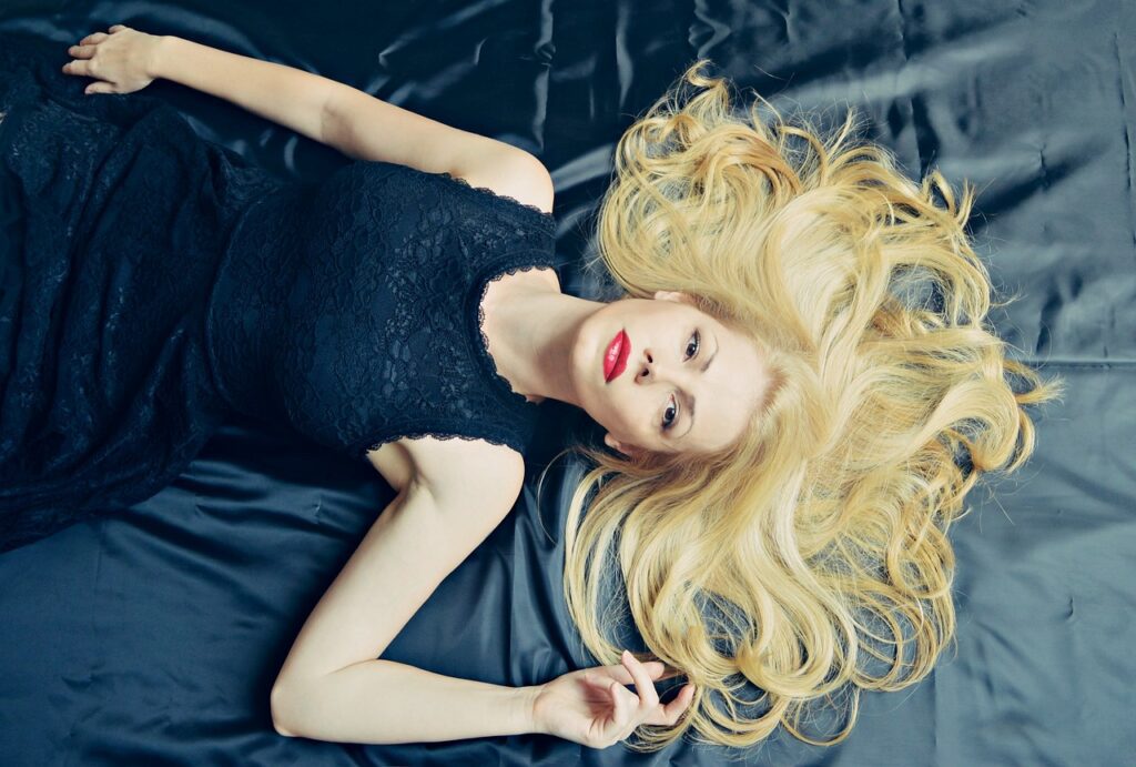 blondynka leżąca na łóżku w ciemnej sukni